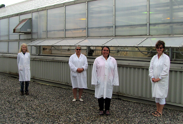 4 women standing outside of a greenhouse